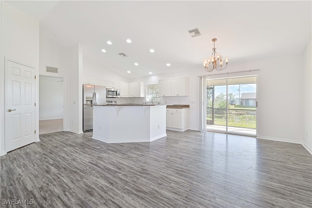 kitchen with a kitchen island, hardwood / wood-style floors, white cabinetry, appliances with stainless steel finishes, and high vaulted ceiling