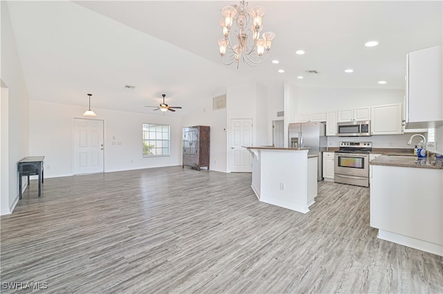 kitchen with hanging light fixtures, stainless steel appliances, sink, a center island, and light hardwood / wood-style floors