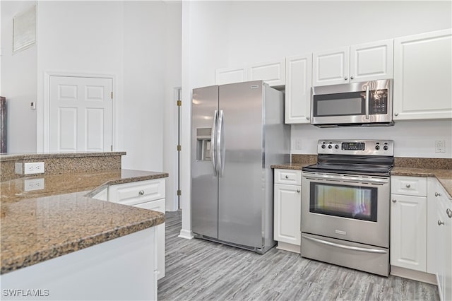 kitchen with appliances with stainless steel finishes, white cabinets, and dark stone counters