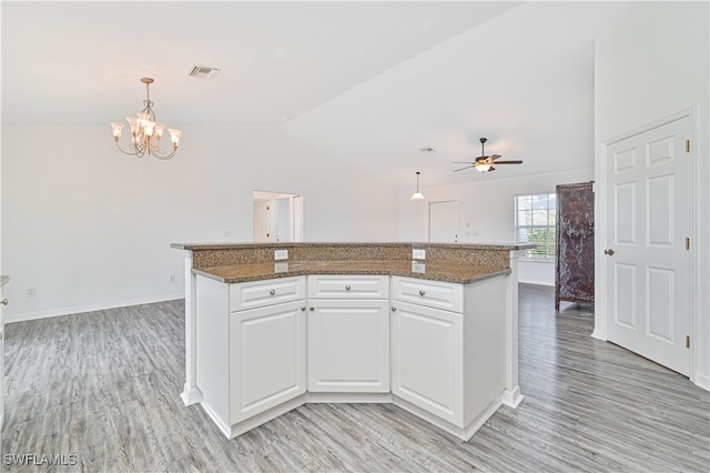 kitchen featuring lofted ceiling, white cabinetry, light hardwood / wood-style flooring, decorative light fixtures, and a center island