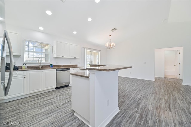 kitchen featuring hanging light fixtures, a center island, light wood-type flooring, stainless steel dishwasher, and white cabinetry