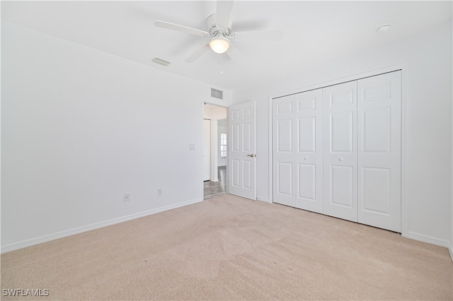 unfurnished bedroom featuring light carpet, a closet, and ceiling fan