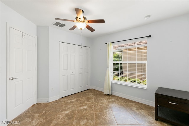 unfurnished bedroom with ceiling fan and a closet