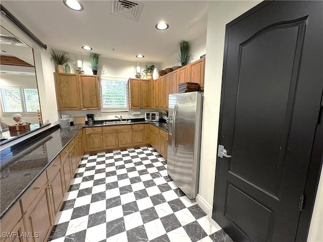 kitchen featuring sink, stainless steel refrigerator with ice dispenser, and dark stone counters