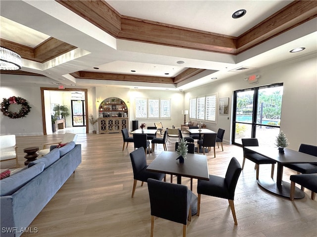 dining area featuring a tray ceiling, ornamental molding, and light wood-type flooring