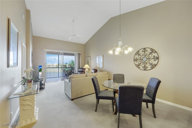 carpeted dining room with ceiling fan with notable chandelier and high vaulted ceiling