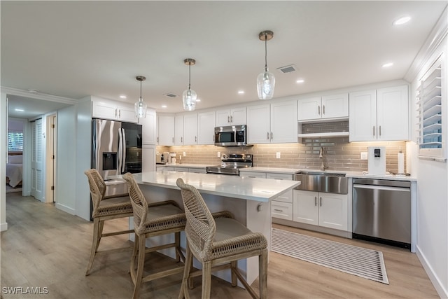 kitchen featuring white cabinets, sink, stainless steel appliances, and hanging light fixtures