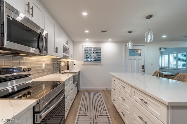 kitchen with sink, white cabinets, hanging light fixtures, and appliances with stainless steel finishes