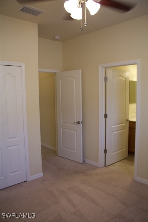 unfurnished bedroom featuring connected bathroom, ceiling fan, and light carpet