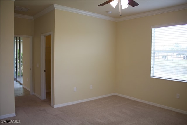 empty room featuring light carpet, crown molding, ceiling fan, and a healthy amount of sunlight