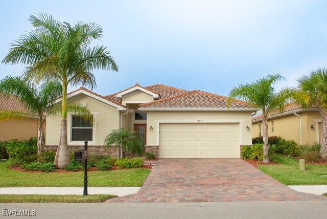 14549 Lanier Ct, Naples, FL 34114 - view of front of home featuring a garage, decorative driveway, stucco siding, stone siding, and a tile roof