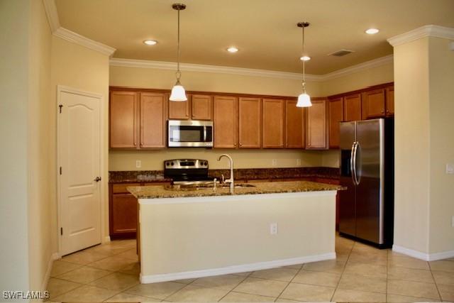 kitchen with sink, hanging light fixtures, dark stone countertops, a kitchen island with sink, and appliances with stainless steel finishes