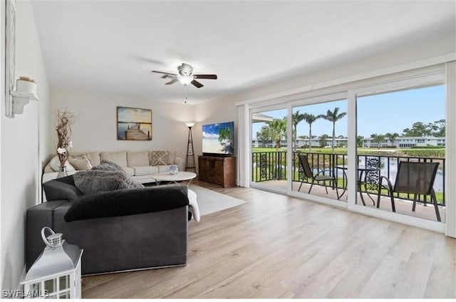 living room with light hardwood / wood-style flooring, a water view, and ceiling fan