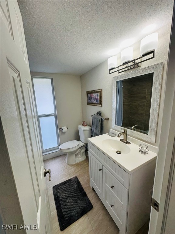 bathroom with toilet, vanity, and a textured ceiling