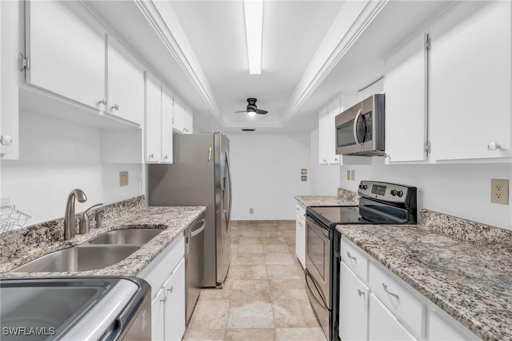 kitchen with white cabinetry, sink, ceiling fan, stainless steel appliances, and a raised ceiling