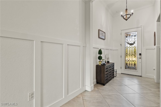 tiled entryway featuring crown molding and a chandelier