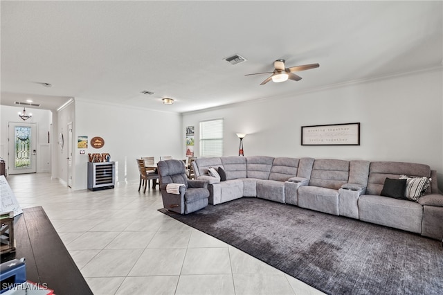 tiled living room with crown molding, ceiling fan with notable chandelier, and beverage cooler