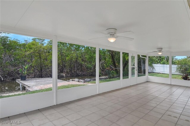 unfurnished sunroom featuring a water view and ceiling fan