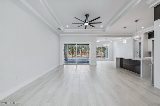 unfurnished living room with light hardwood / wood-style flooring, a raised ceiling, ceiling fan, and sink