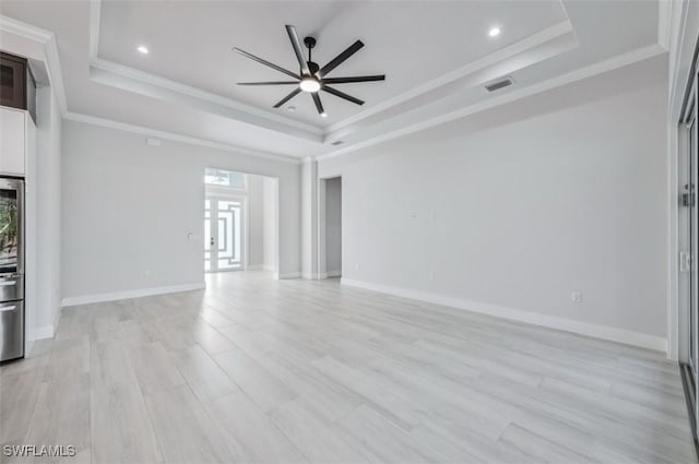 unfurnished living room with a raised ceiling, crown molding, ceiling fan, and light hardwood / wood-style floors