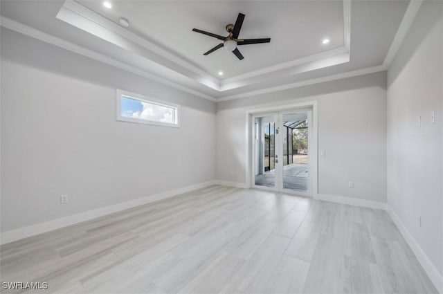 empty room with ceiling fan, light hardwood / wood-style floors, a raised ceiling, and ornamental molding