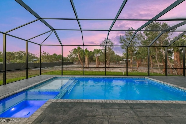 pool at dusk featuring an in ground hot tub, a patio area, and a lanai