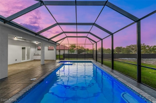 pool at dusk featuring a lanai, ceiling fan, french doors, and a patio