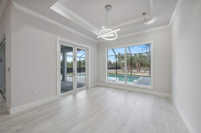 unfurnished room with an inviting chandelier, a raised ceiling, ornamental molding, and light hardwood / wood-style floors