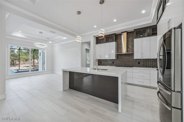 kitchen featuring stainless steel refrigerator, white cabinetry, wall chimney range hood, decorative light fixtures, and decorative backsplash