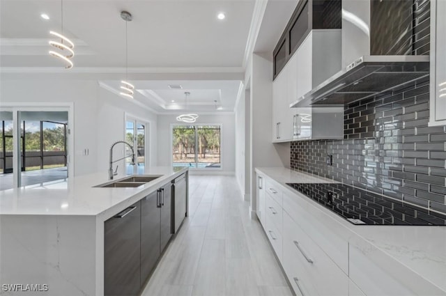 kitchen featuring decorative backsplash, sink, wall chimney range hood, decorative light fixtures, and white cabinets