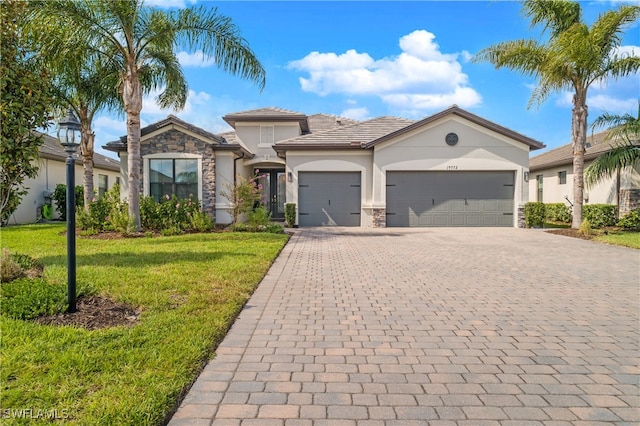 view of front of property with decorative driveway, stone siding, a front yard, and an attached garage