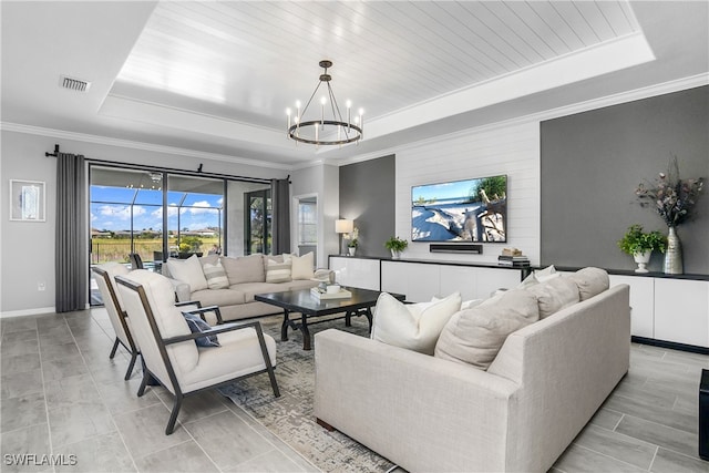 living room featuring a raised ceiling, ornamental molding, and a notable chandelier