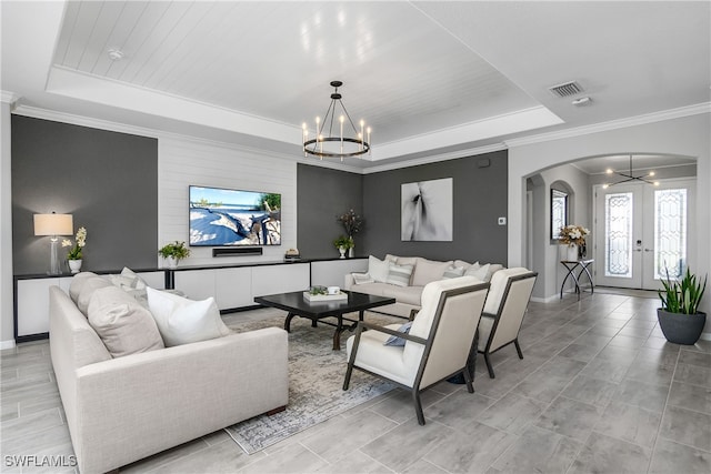 living room featuring a tray ceiling, crown molding, french doors, and an inviting chandelier