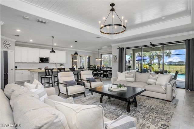 living room featuring a raised ceiling, light tile patterned floors, ornamental molding, and an inviting chandelier