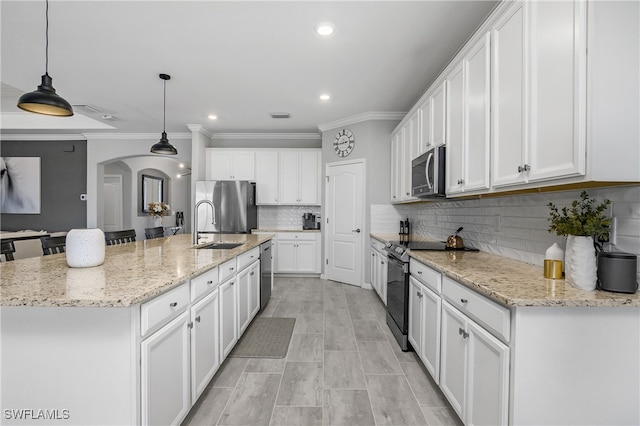 kitchen with white cabinets, sink, hanging light fixtures, an island with sink, and stainless steel appliances