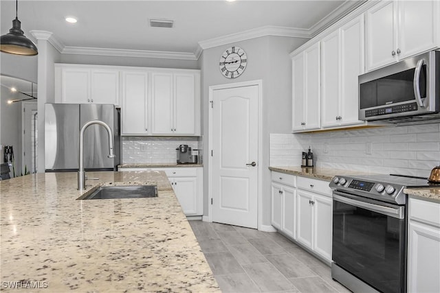 kitchen with a sink, appliances with stainless steel finishes, white cabinets, and crown molding