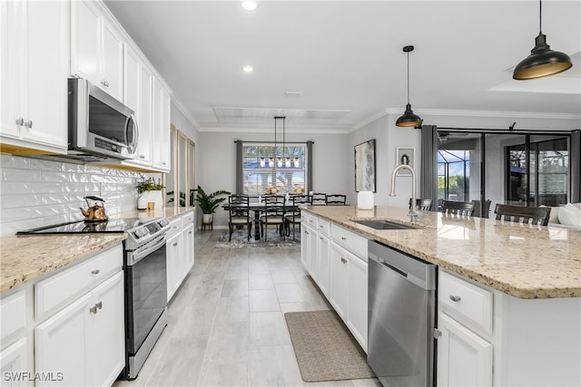 kitchen featuring stainless steel appliances, sink, decorative light fixtures, white cabinetry, and an island with sink