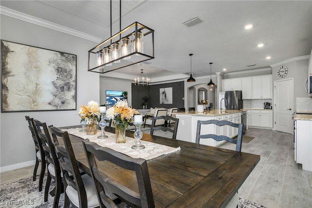 dining room with sink, light tile patterned floors, crown molding, and a chandelier