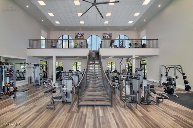 gym featuring a high ceiling, a paneled ceiling, baseboards, and wood finished floors