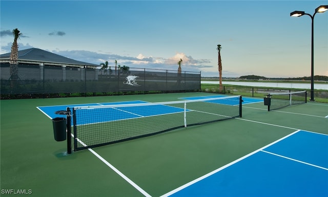 view of tennis court with basketball court and a water view