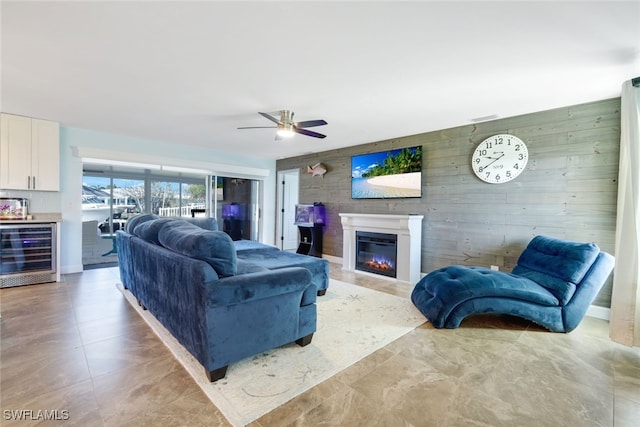 living room with wood walls, ceiling fan, and beverage cooler