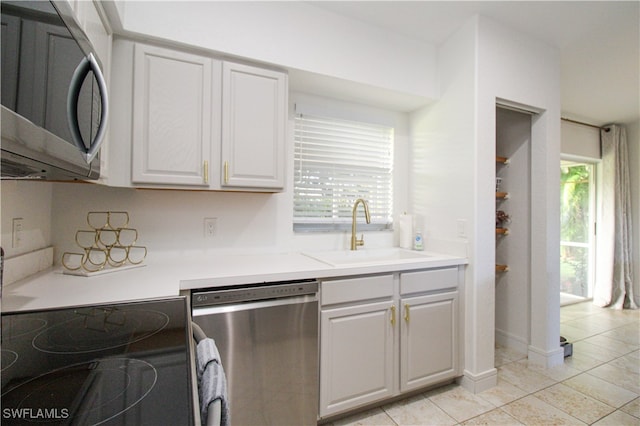 kitchen featuring white cabinetry, stainless steel appliances, sink, and light tile patterned floors