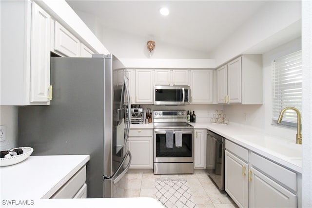 kitchen with sink, light tile patterned flooring, appliances with stainless steel finishes, and lofted ceiling