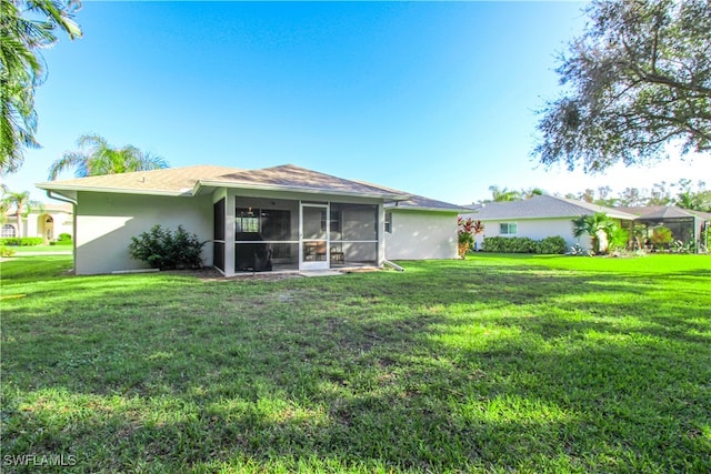 rear view of property featuring a yard and a sunroom