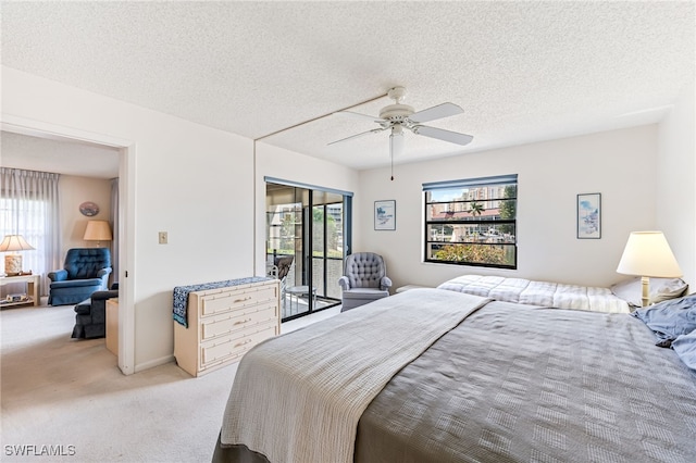 carpeted bedroom with a textured ceiling, access to exterior, and ceiling fan