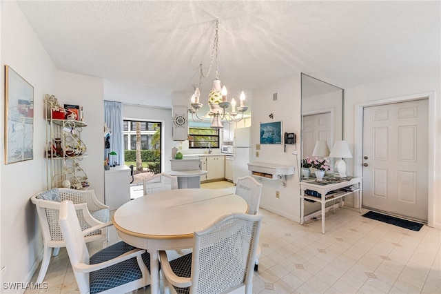 tiled dining area with sink, a chandelier, and a textured ceiling