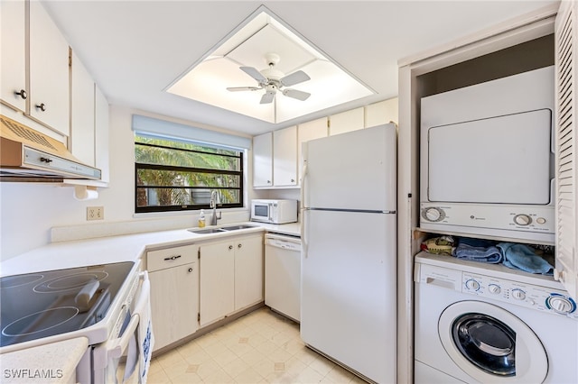 kitchen with white appliances, sink, ceiling fan, stacked washer and dryer, and white cabinets