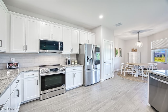 kitchen featuring stainless steel appliances, white cabinets, backsplash, and pendant lighting