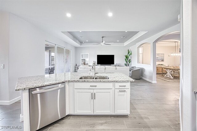 kitchen featuring dishwasher, a raised ceiling, ceiling fan, sink, and white cabinetry