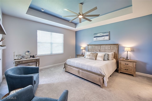 bedroom featuring ceiling fan, light colored carpet, and a raised ceiling